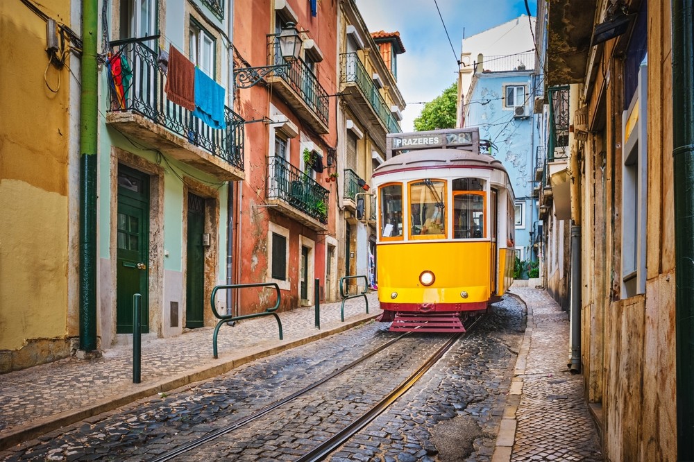 Gul spårvagn på en kullerstensgata i Lissabon