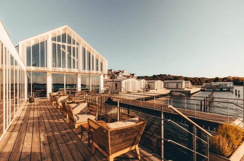 Gullmarsstrands terrass med sittgrupper, stora glasfasader och bryggor vid Gullmarsfjorden.