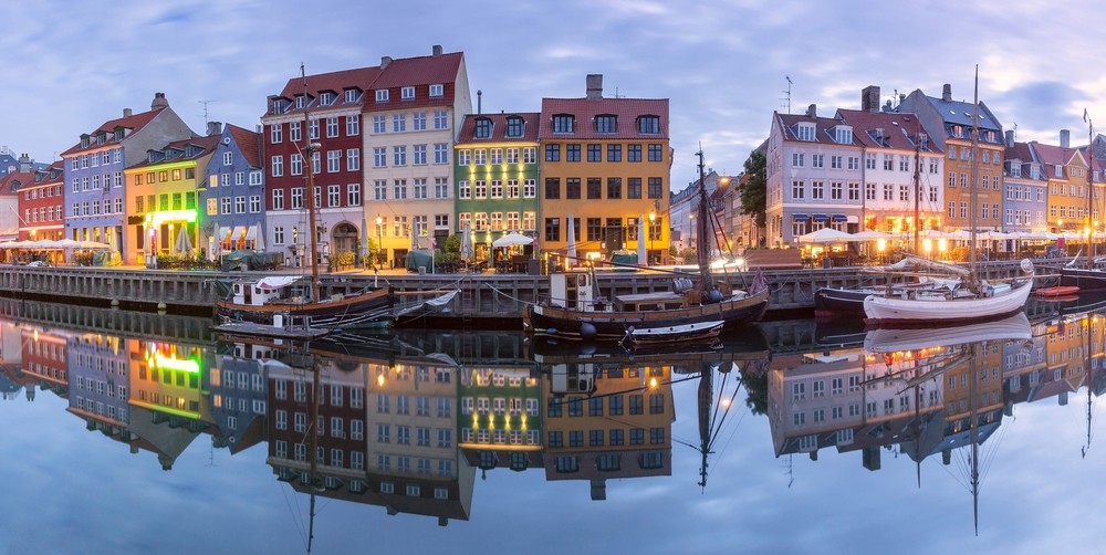 Färgglada hus och båtar längs Nyhavn i Köpenhamn i kvällsljus.