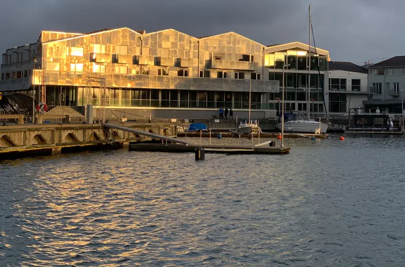 Marstrands Havshotell vid kajen med solbelyst fasad och båtar i förgrunden.