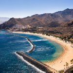 Playa de las Teresitas på Teneriffa med gyllene sand, palmer och berg runt bukten.