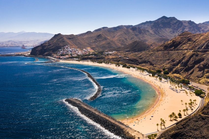 Playa de las Teresitas på Teneriffa med gyllene sand, palmer och berg runt bukten.