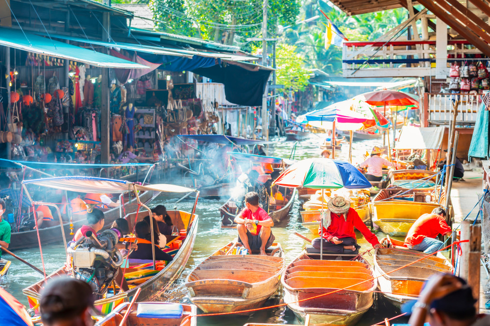 Flytande marknad i Bangkok med longtailbåtar och försäljare.