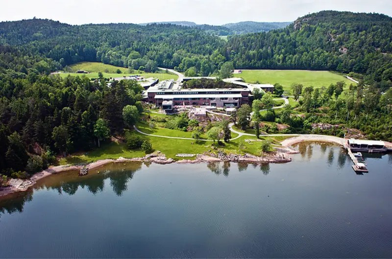 Flygvy över VANN vid Gullmarsfjorden, omgivet av skog med strand och brygga framför hotellet.
